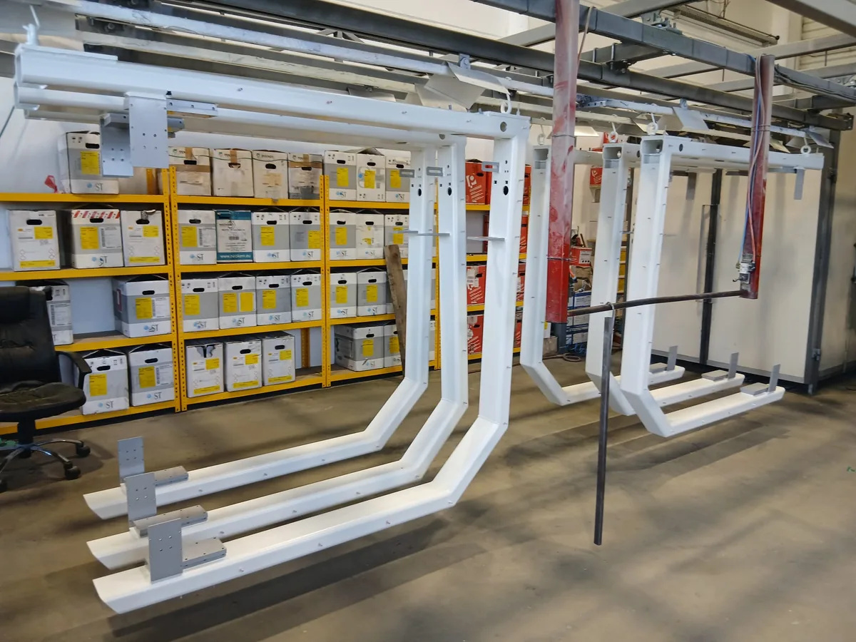 Große Maschinengestelle in Verkehrsweiß pulverbeschichtet hängen an der Förderbahn in der Halle